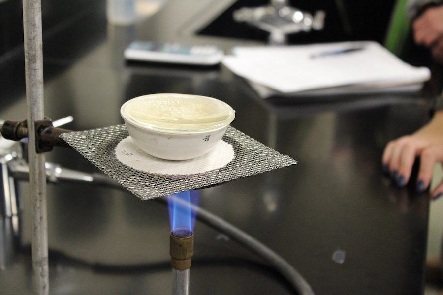 The liquids of zinc nitrate being evaporated with a bunsen burner. 