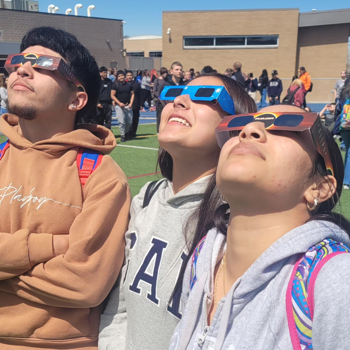 Senior Beau Johnson, Jaliyah Mora, and Joseline Ortiz peer at the eclipse through their special glasses. 