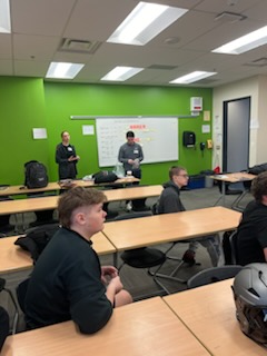 Football players listen to several representatives from Riddell Axiom. They helped students understand the technology in the new helmets.