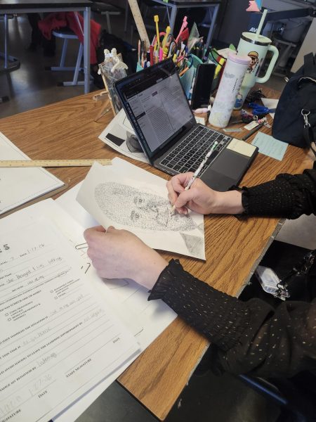 Almira Winans works on a piece of art using pencil. She is using the words of the subject to create the art piece.